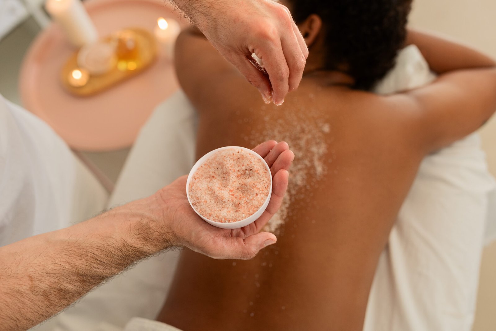 African American lady enjoys back scrub at spa A serene image of a black lady lying on her stomach enjoying a spa back scrub with visible scrub particles on her skin