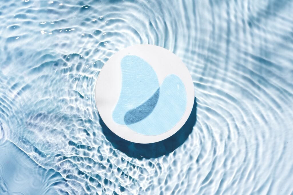 Parches cosméticos flotando en agua para tratamientos de hidratación y cuidado facial.