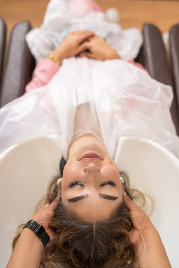 Mujer recibiendo un masaje relajante del cuero cabelludo en un salón de belleza.